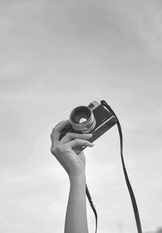 一眼レフカメラを持っている手のモノクロ写真